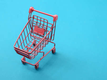 Mini pink supermarket trolley on blue background. shopping conceptの写真素材