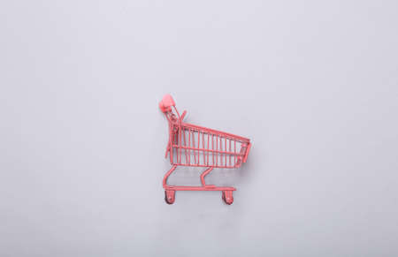 Mini pink supermarket trolley on gray background. top view. minimalism. flat layの写真素材