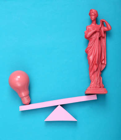 Balancing swing with light bulb and antique greek statue on blue background. creative layout. fresh ideas. concept art. flat lay. top viewの写真素材