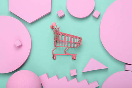creative shopping layout. Pink supermarket trolley with pink different geometric shapes on mint blue background. Pastel color trend. minimalism. concept art. flat lay. top view.の写真素材