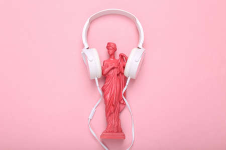 creative music layout. Pink Antique greek goddess statue with headphones on pink background. flat lay. top viewの写真素材