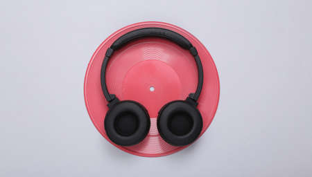 creative music layout. Pink vinyl record and headphones on gray background. minimalism. flat lay....