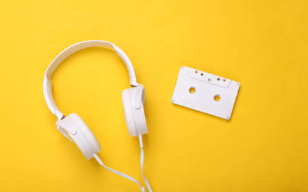 White headphones with audio cassette on yellow background. creative music layout. top view. flat layの写真素材