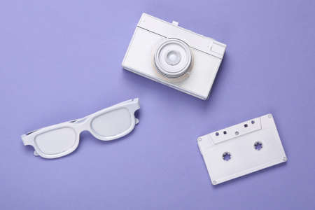 Minimalistic layout of white audio cassette, glasses, camera on purple background. top view. flat layの写真素材