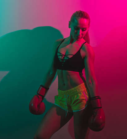 Fashion Fit woman boxer in boxing gloves. Pink green neon lightの写真素材