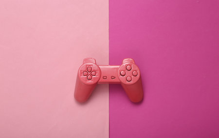 creative gaming layout. Pink retro gamepad on pink background. minimalism. concept art. Modern still life. flat lay. top view.の写真素材