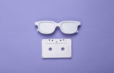 Minimalistic layout of white audio cassette, glasses on purple background. top view. flat layの写真素材