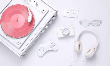 retro creative layout. White vinyl record player, camera, gamepad, audio cassette, glasses, headphones on a white background. top view. flat layの写真素材