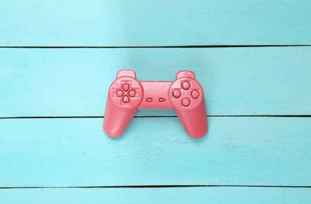 creative gaming layout. Pink retro gamepad on blue wooden background. minimalism. concept art....