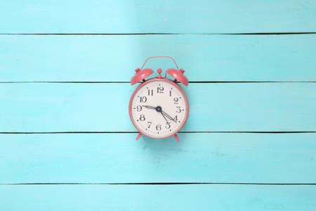 creative layout. Pink alarm clock on blue wooden background. top view. flat layの写真素材
