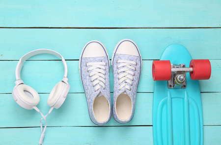 creative layout. Sneakers, headphones and penny poard on blue wooden background. minimalism. top view. flat layの写真素材