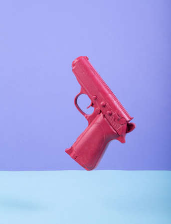 Levitating pink gun on colored background. Minimalistic still life. creative layout. concept art