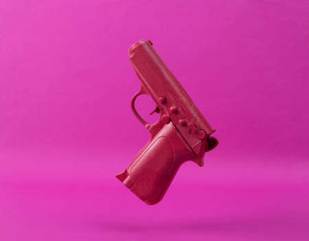 Levitating pink gun on pink background. Minimalistic still life. creative layout. concept artの写真素材