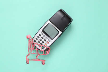 Pink mini shopping cart with pos terminal on blue backgroundの写真素材