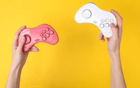 Female hands hold retro gempads on yellow background. gaming concept