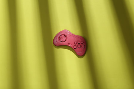 Pink gamepad on a green background with trendy striped shadow. minimalism. abstraction. concept art