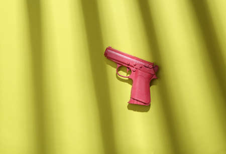 Pink gun on green background with trendy striped shadow. minimalism. abstraction. concept art. creative layoutの写真素材