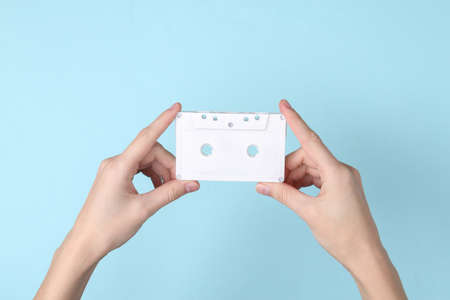 Female hands holding audio cassette on blue background. Music minimal conceptの写真素材