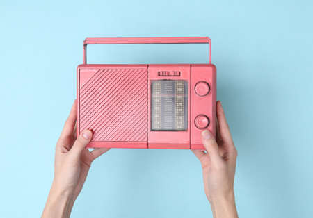 Female hands holding pink fm radio receiver on blue background. Music minimal conceptの写真素材