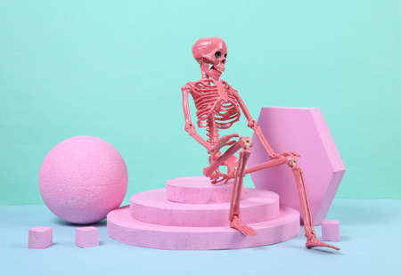 Skeleton sitting on podium with pink geometric shapas. concept art. Minimalism halloween conceptの写真素材