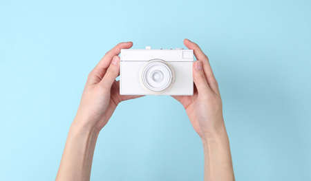 Hands holding white camera on blue background. minimalismの写真素材