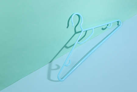 Hanger on blue background with trendy shadows. creative layout. Minimalistic still lifeの写真素材