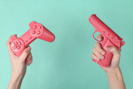 Female hands hold pink retro gempad and gun on blue background. retro video gameの写真素材