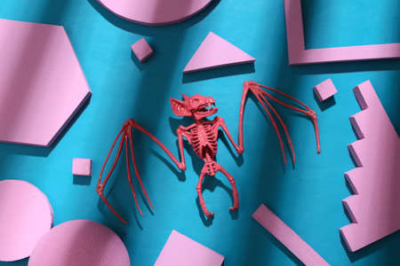 Pink bat skeleton with geometric shapes on a blue background with trendy striped shadow. creative layout. top viewの写真素材