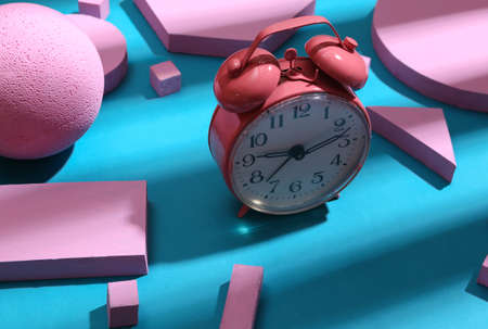 Pink alarm clock and pink geometric shapes on blue background with trendy striped shadow. creative...