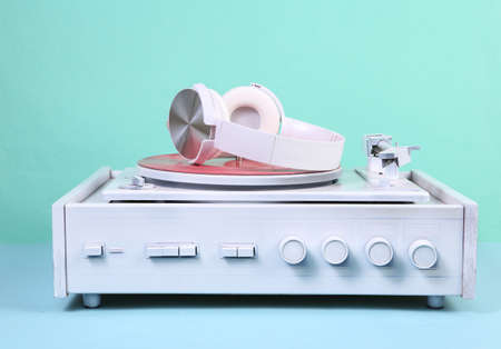 White vinyl record player and headphones on blue background. DJ equipment. Minimalism music concept....