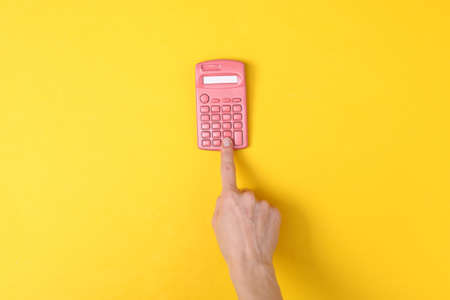 Hand using pink calculator on yellow background. minimalismの写真素材
