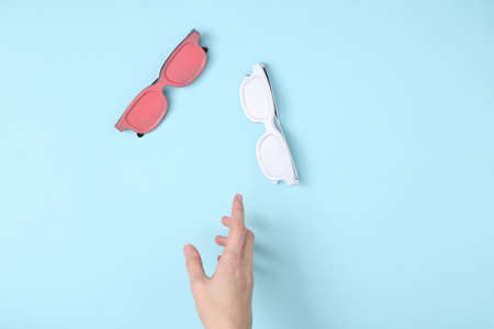 The hand reaches for the glasses on a blue background. minimalism