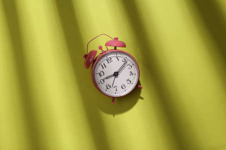 Alarm clock on green background with trendy striped shadow. minimalism. abstraction. concept artの写真素材