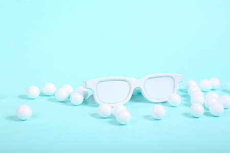 Glasses with white balls on blue background. Minimalism still life. creative layoutの写真素材