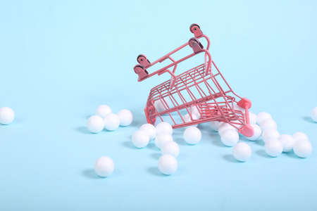 Mini Shopping cart with white balls on a blue background. Minimalism shopping still lifeの写真素材
