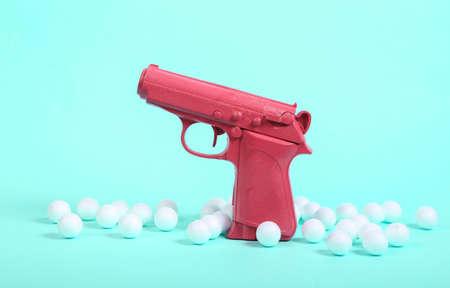Pink gun with white balls on blue background. Minimalism still life. creative layoutの写真素材