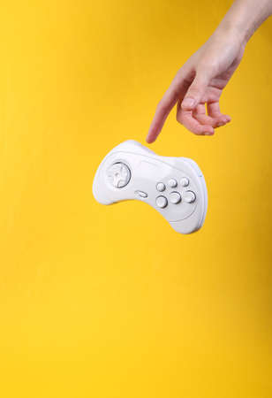 Hand and Levitating white gamepad on yellow background. Minimalistic still life. concept art. video gameの写真素材