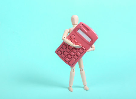 Wooden puppet holding pink calculator on blue backgroundの写真素材