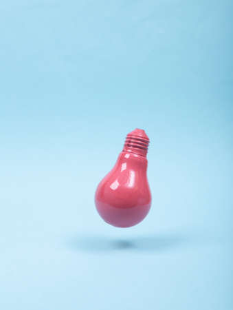 Levitating pink light bulb on blue background. 3D photo. Minimalistic still life. creative idea layout. concept artの写真素材