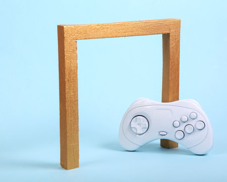 White gamepad with golden frame arch on blue background. Minimalism still life. concept artの写真素材