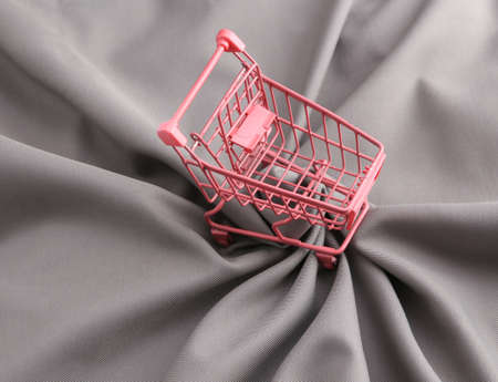 Pink shopping cart on gray silk background