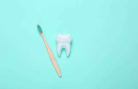 Eco-friendly bamboo toothbrush and tooth on blue background. Dental care concept. top view.の写真素材