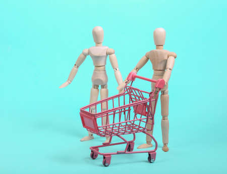 Puppets with a mini shopping trolley on a blue background. shopping conceptの写真素材