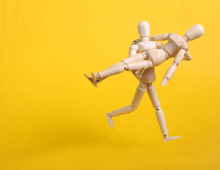 Wooden Puppet run in arms with puppet on yellow background
