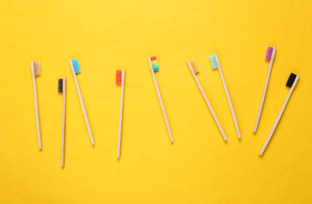 Many Eco-friendly bamboo toothbrushes on yellow background. top view.の写真素材