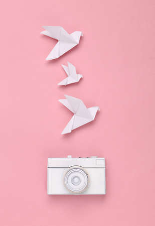 White painted camera and origami doves on a pink pastel background. minimalismの写真素材