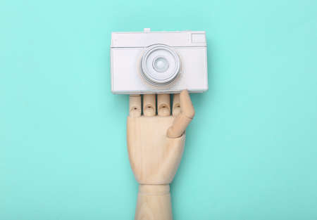 Wooden hand holding White painted camera on blue background. minimalismの写真素材
