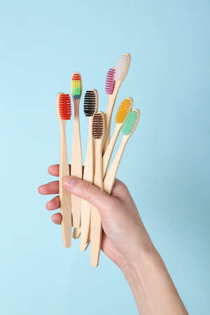 Hands holding Eco-friendly bamboo toothbrushes on blue background. dental care.の写真素材