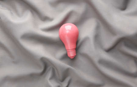 Pink light bulb on gray silk backgroundの写真素材