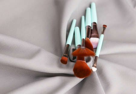 Makeup brushes on a gray silk background. beauty still life.